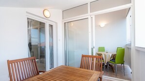 Een houten tafel en stoelen in een kamer met een schuifdeur naar een balkon.