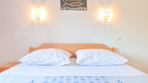 Una cama con dos almohadas blancas, un cabecero de madera y una colcha azul estampada con flores.