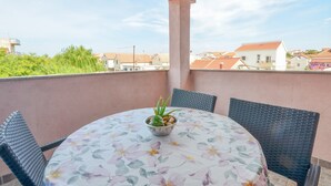 Una mesa redonda con mantel floral, rodeada de sillas de mimbre y una pequeña planta en maceta sobre la mesa.
