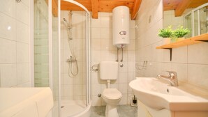 A bathroom with a glass-enclosed shower, a toilet, a sink, and a towel rack. - Apartment with old town view no.2 (Pirovac)