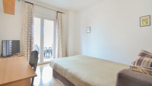 A bedroom with a bed, a desk with a TV, a chair, and a window with curtains. - Apartment with old town view no.2 (Pirovac)