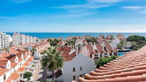 Eine Küstenstadt mit terrakottafarbenen Dächern, blauem Himmel und Blick auf das Meer.