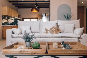 A modern living room with a sofa, decorative fish, a cactus, and a tray with various items.