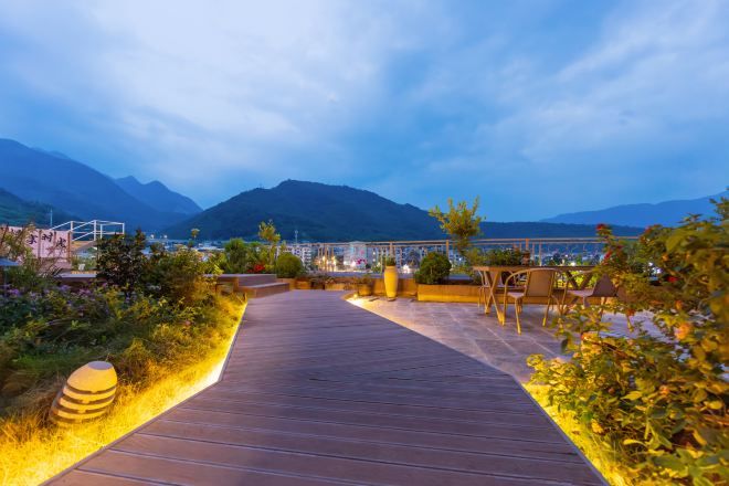 A wooden pathway leading to a seating area with a mountain view.