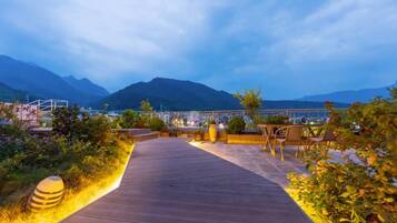 A wooden pathway leading to a seating area with a mountain view.