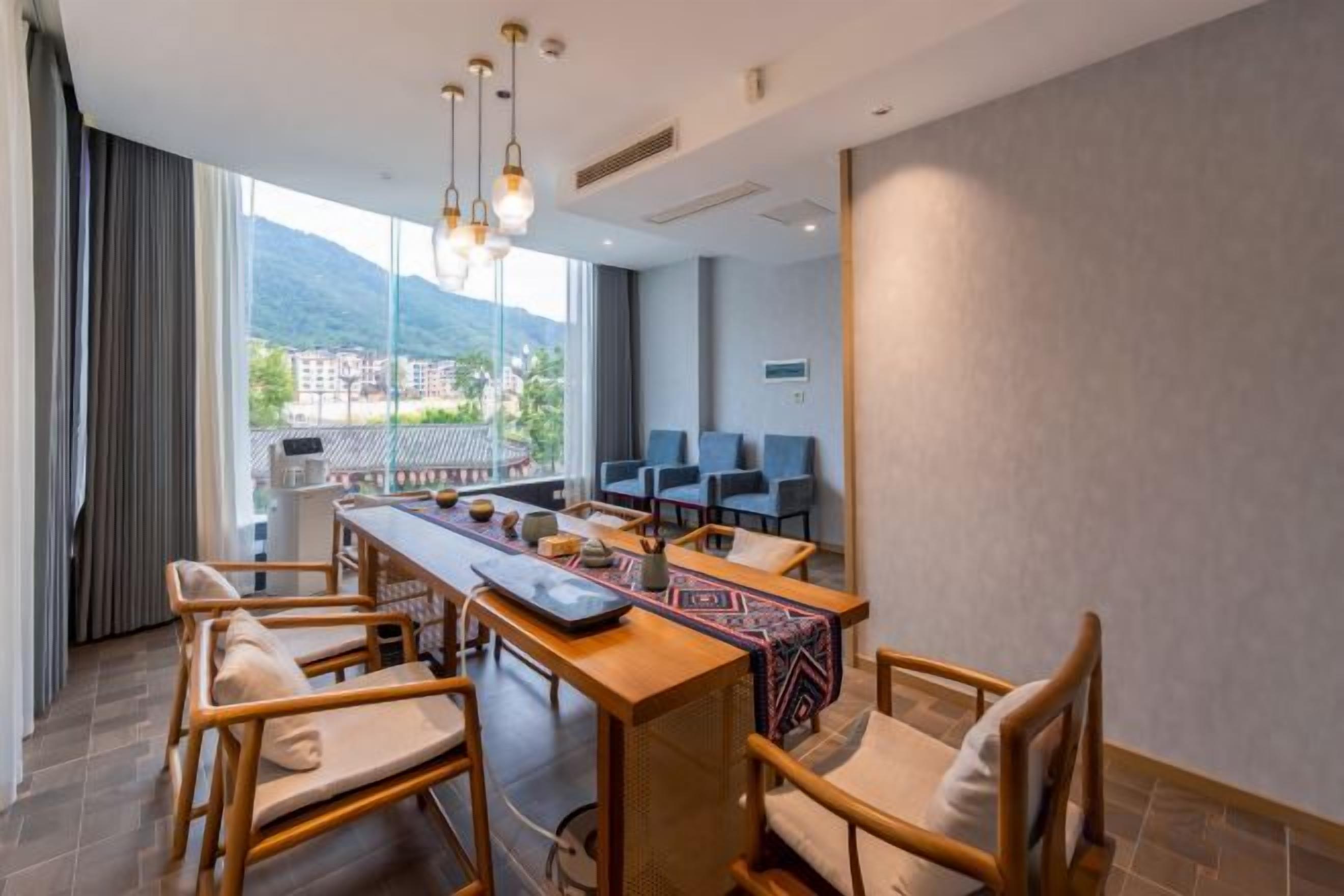 A modern hotel room with a dining area, a balcony with a view, and a large window.