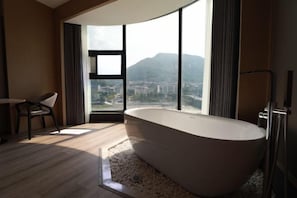 Een moderne badkamer met een vrijstaand bad, grote ramen met uitzicht over de stad, en een minimalistisch design.