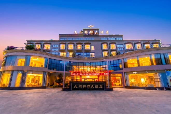 A multi-story hotel with a prominent entrance, large windows, and a well-lit facade.