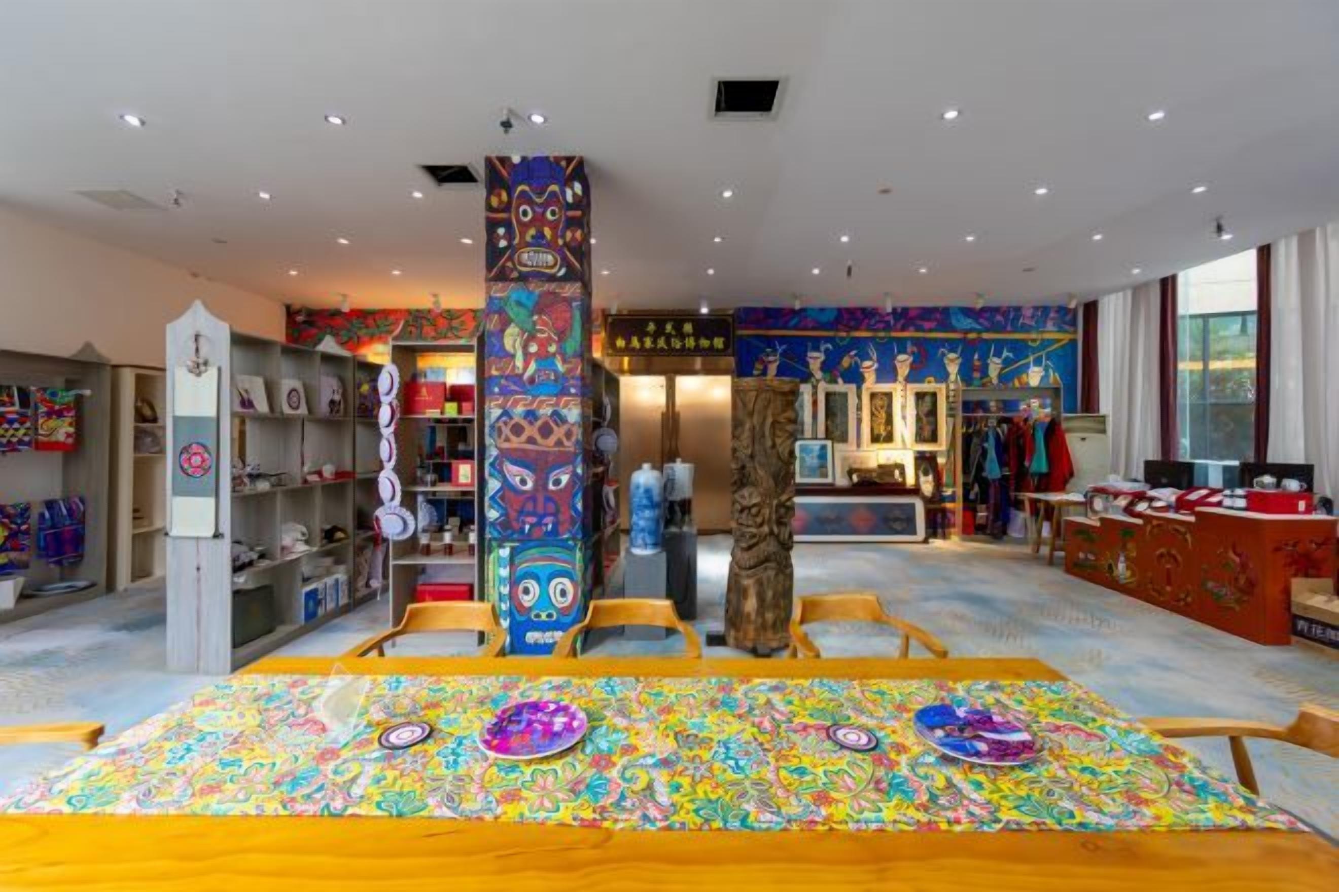 A room with a large wooden table, a colorful patterned rug, and a tall decorative pillar.