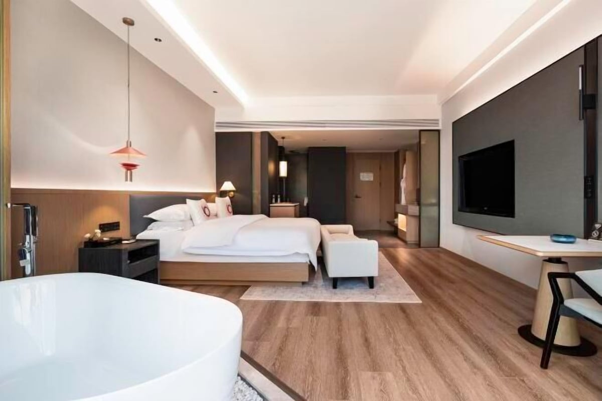 Een moderne hotelkamer met een groot bed, een zithoek, een bureau, een flatscreen televisie en een ruime badkuip.