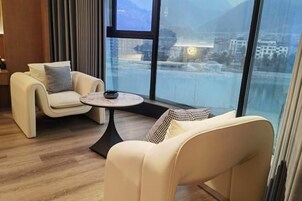 Una habitación moderna con dos sofás y una mesita, grandes ventanales con vistas a un paisaje nevado.