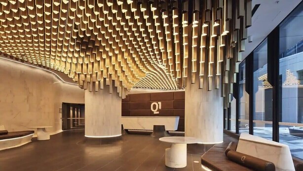 A modern lobby with a unique ceiling design, a reception desk, and seating areas. - Lovely 3BR Apt with Panoramic Views, FREE Parking (Melbourne)