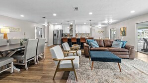 A spacious living area with a dining set, a leather sofa, and a kitchen in the background. - VRCC Villa Golden Retreat (Cape Coral)