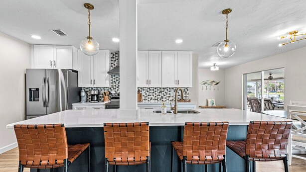 A modern kitchen with a central island, stainless steel appliances, and pendant lighting. - VRCC Villa Golden Retreat (Cape Coral)