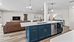 A modern kitchen with a central island, blue cabinets, and pendant lighting. - VRCC Villa Golden Retreat (Cape Coral)