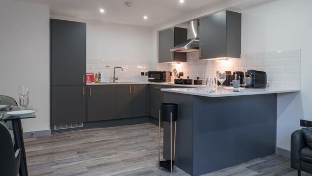 A modern kitchen with grey cabinets, a white countertop, and a central island. - Spacious 1BED Flat in Central Preston fast WiFi (Preston)
