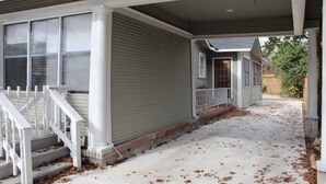 Ein Wohnhaus mit überdachter Veranda, einer einladenden Haustreppe und einer Auffahrt.