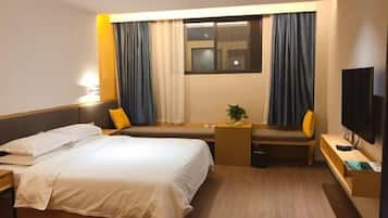 A hotel room with a bed, a desk, a chair, a TV, and a window with curtains.