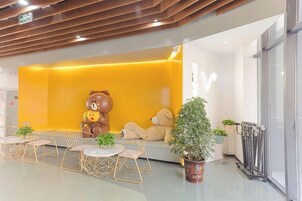 Un vestíbulo con una gran estatua de un oso, zona de estar y plantas en macetas.