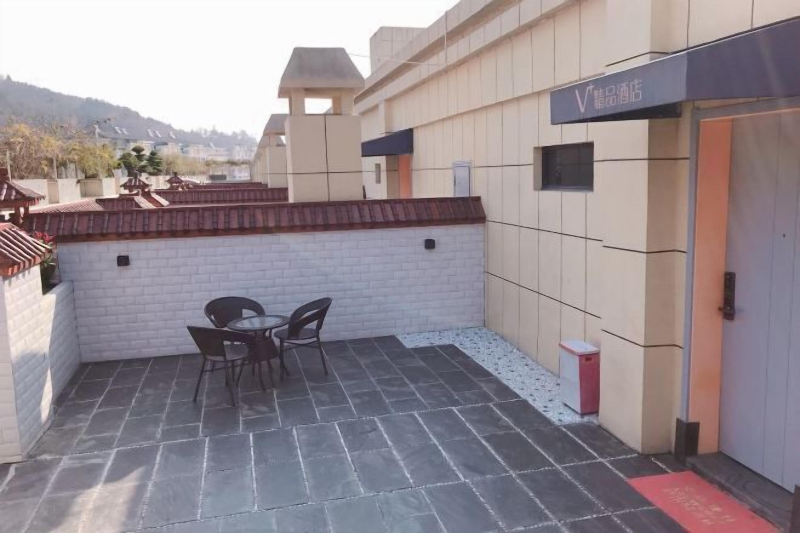 A rooftop patio with a table and chairs, a small trash bin, and a building entrance.
