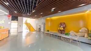 A modern lobby with a wooden ceiling, a yellow wall with a bear sculpture, and a staircase in the background. - Mini Home Boutique Hotel (Shiquan)