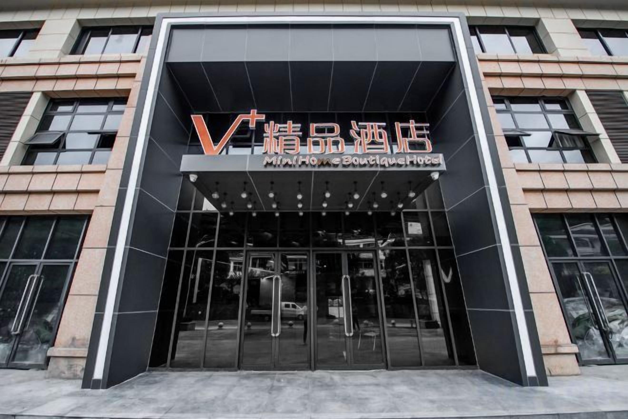 A modern building entrance with a glass facade and a sign indicating a boutique hotel.