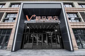 A modern building entrance with a glass facade and a sign indicating a boutique hotel. - Mini Home Boutique Hotel (Shiquan)