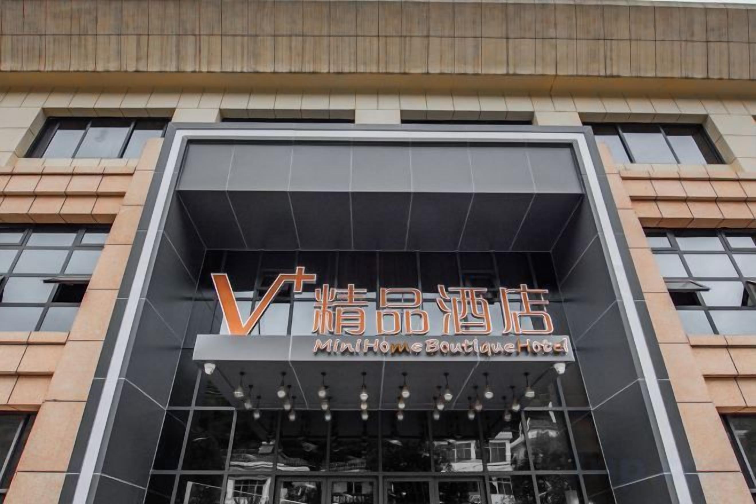 Un bâtiment à la façade moderne, orné d’une enseigne bien visible avec des caractères chinois et le texte en anglais « MinHome Boutique Hotel ».