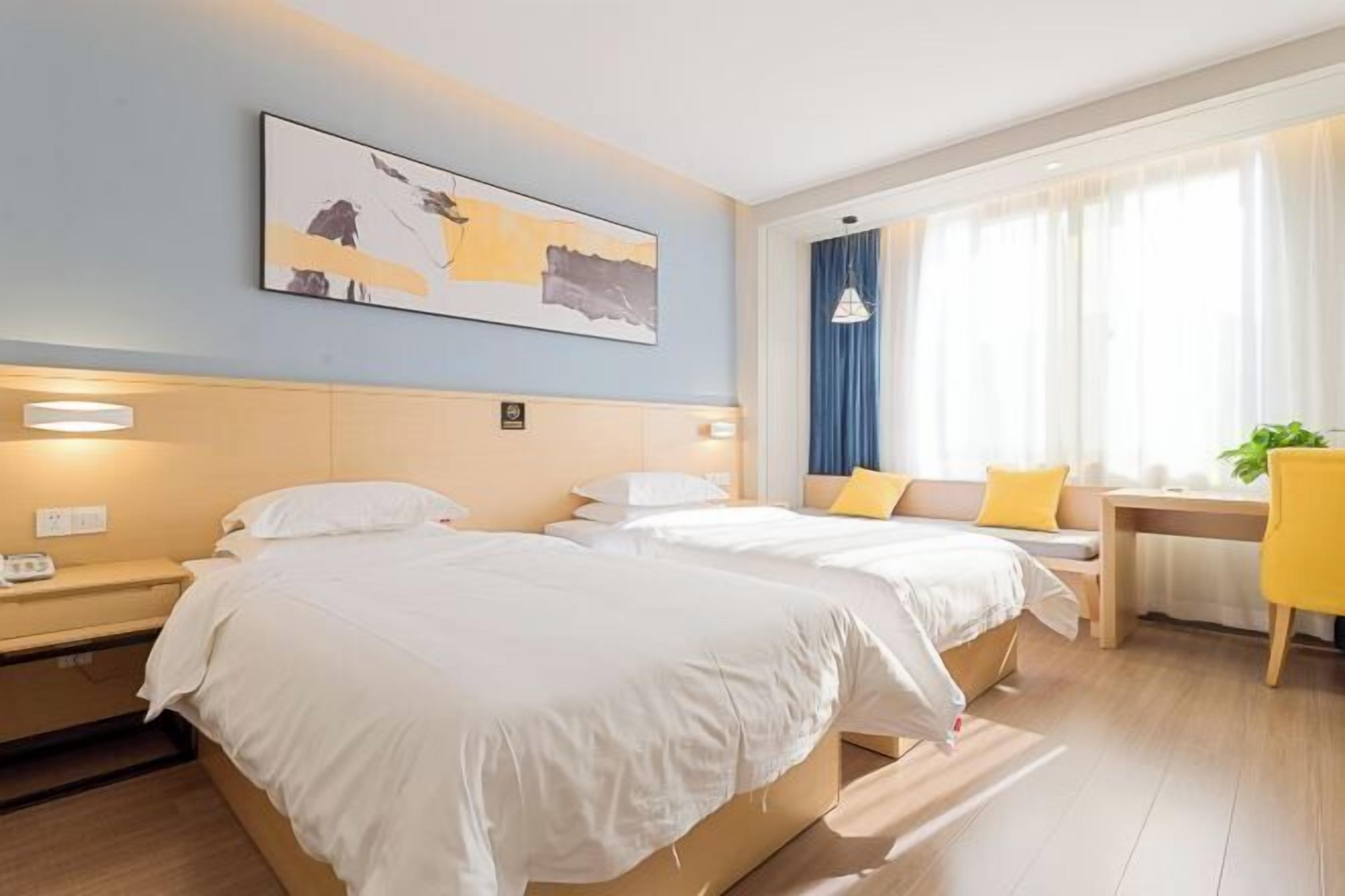 A hotel room with two beds, a desk, a chair, a window with curtains, and a painting on the wall.