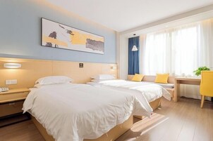 Habitación de hotel con dos camas, un escritorio, una silla, un ventanal con cortinas y un cuadro en la pared.