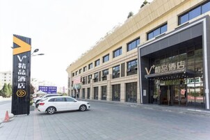 Entrada de hotel con un cartel que indica una sección VIP, fachada de edificio moderno y un coche estacionado.