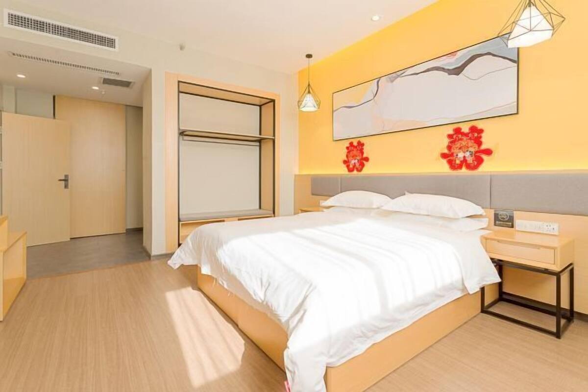 A modern hotel room with a large bed, a bedside table, and a wall-mounted TV.