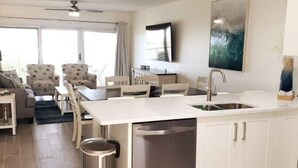 Une cuisine moderne avec des meubles blancs, un lave-vaisselle en acier inoxydable et un coin repas comprenant une table et des chaises.