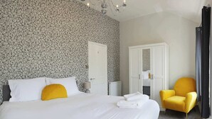 A hotel room with a large bed, a wardrobe, a chair, and a mirror.