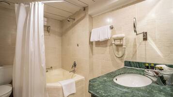 A bathroom with a bathtub, a shower curtain, a toilet, a sink, and a towel rack.