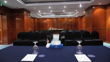 A conference room with a long table, black chairs, and a blue tablecloth.