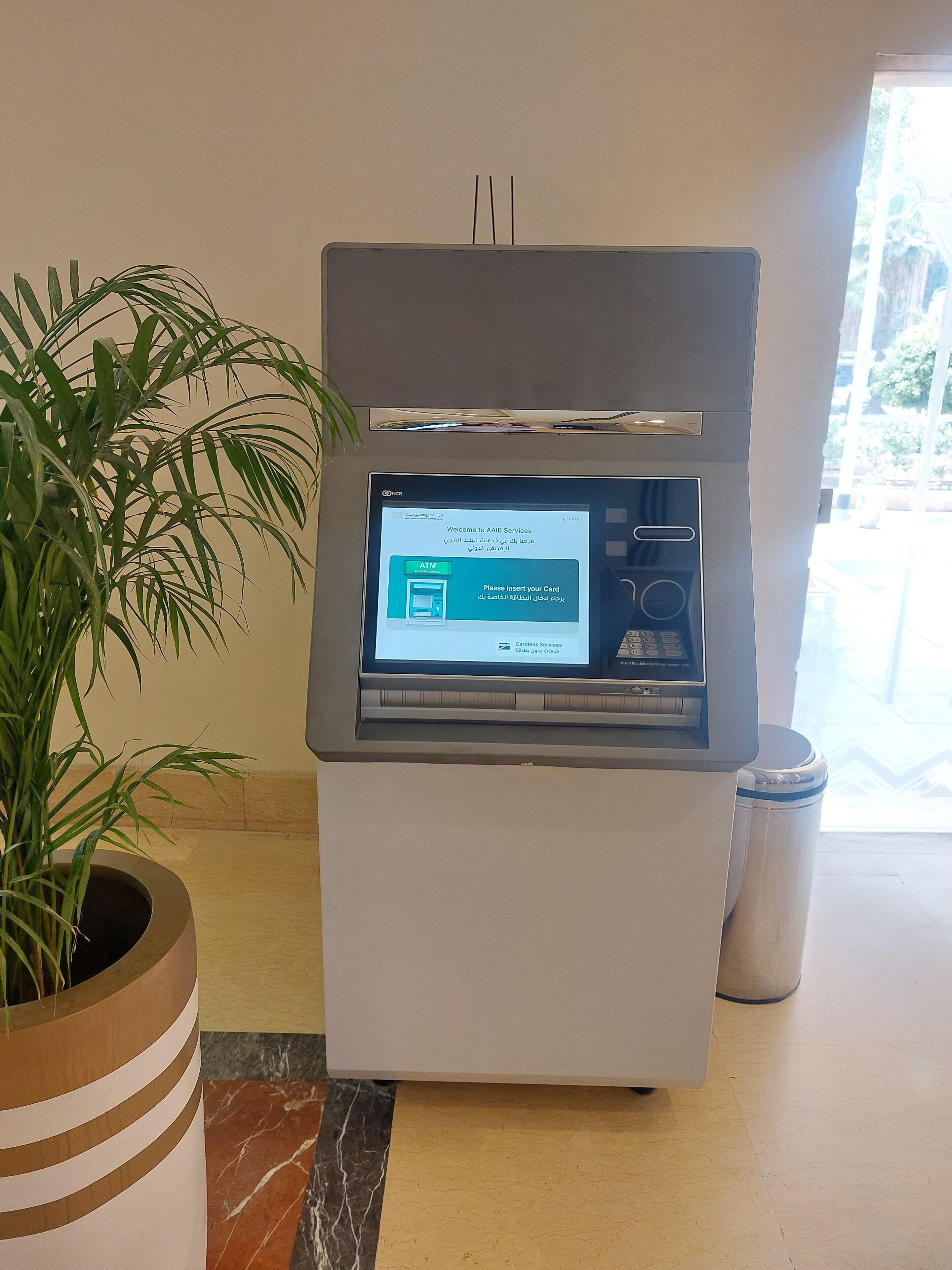 Cajer automàtic amb pantalla digital que mostra "Benvingut a AAIB Services" i "Si us plau, insereix la teva targeta" en diversos idiomes.