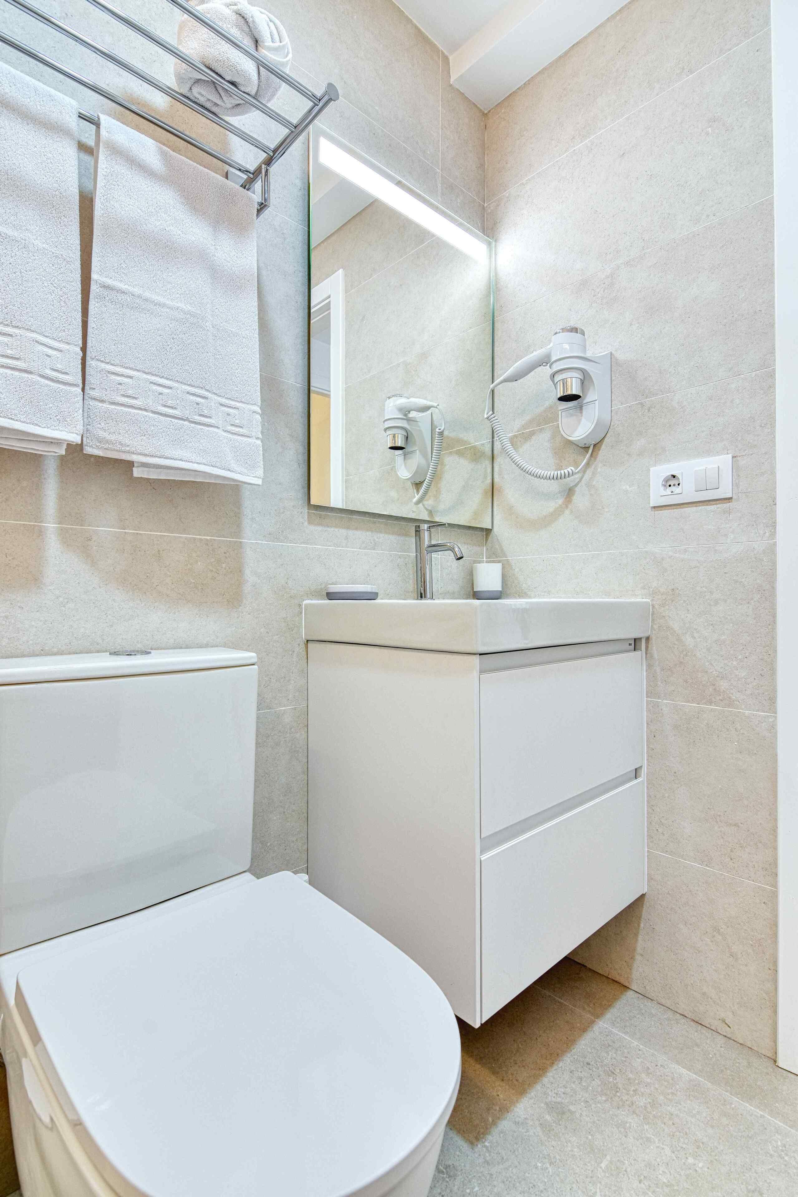 A modern bathroom with a toilet, sink, and towel rack.