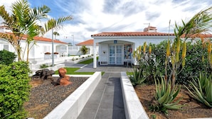 A hotel with a white facade, red-tiled roof, and a covered entrance. - Bungalows Adonis (San Bartolomé de Tirajana)