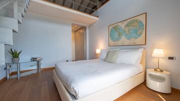 Camera da letto moderna con un letto grande, un tavolino in vetro con una pianta, una mappa appesa al muro e una scala.