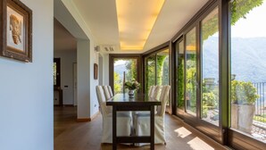A dining area with a table and chairs, large windows with a mountain view, and a framed picture on the wall.
