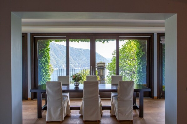 A dining area with a table and chairs, large windows with a mountain view, and a stone sculpture on the windowsill.