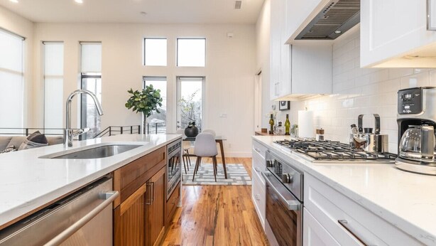 A modern kitchen with a large island, stainless steel appliances, and a view of the outdoors. - Stylish & Perfectly Located Deluxe 2-Bed Townhome (Dallas)