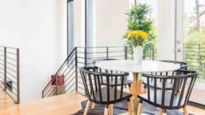 A dining area with a round table and chairs, a black rug, and a potted plant. - Glamorous Perfectly Located Deluxe 2 Bed Townhome (Dallas)