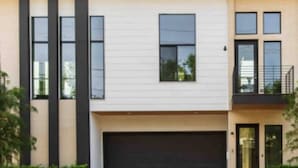 A modern two-story house with a garage, large windows, and a flat roof. - Glamorous Perfectly Located Deluxe 2 Bed Townhome (Dallas)