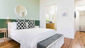 A bedroom with a bed, a bedside table, a mirror, and a wardrobe. - Glamorous Perfectly Located Deluxe 2 Bed Townhome (Dallas)