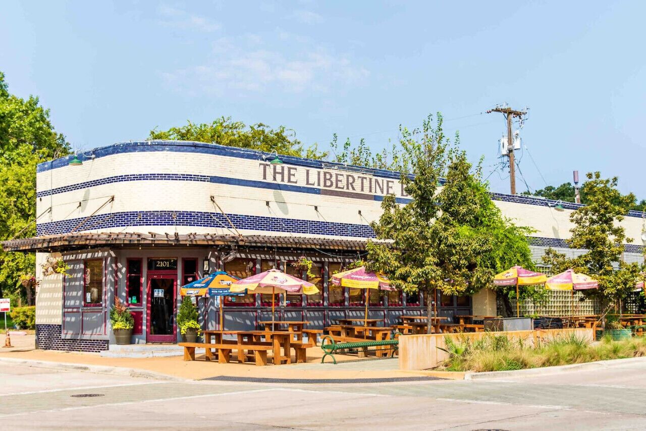 Un restaurante llamado "The Libertine" con terraza y fachada azul y blanca.