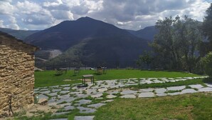 A stone building with a grassy area and tables. - Eco dos Teixos (Carballeda de Valdeorras)