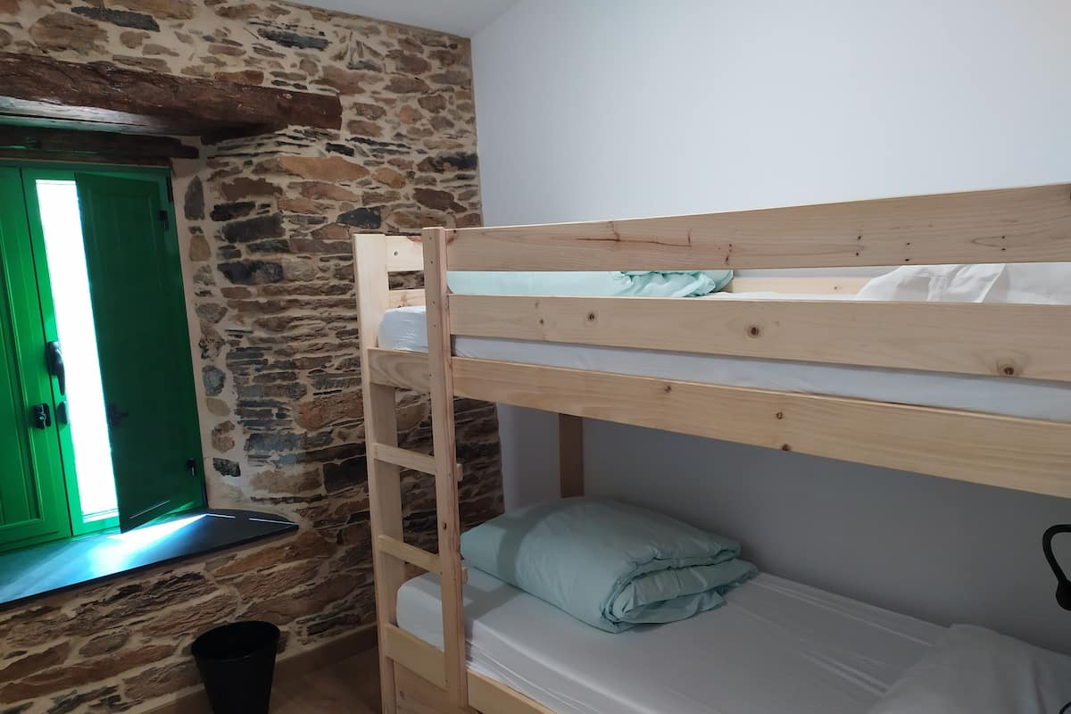 Un lit superposé dans une pièce avec un mur en pierre et une porte verte.