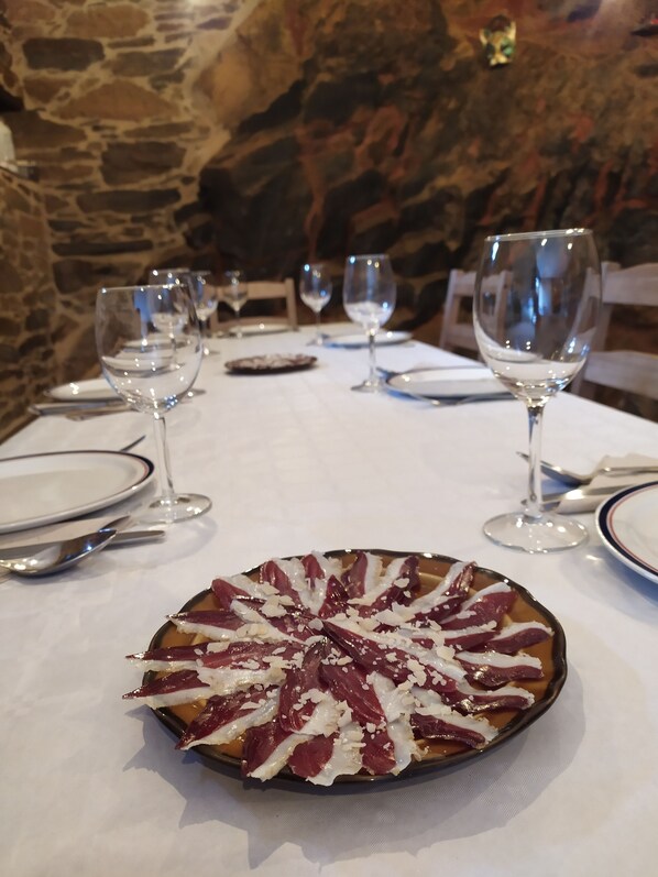 Una mesa de comedor con un plato de comida, copas de vino y cubiertos.